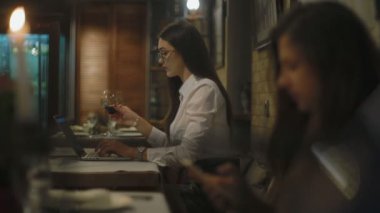 kafede dizüstü bilgisayar ile masada kırmızı şarap içme gözlüklü esmer kadın