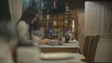 kırmızı şarap içme ve kafede dizüstü bilgisayar ile çalışma gözlüklü esmer kadın