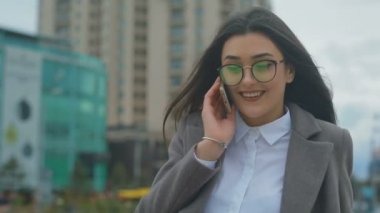 smartphone üzerinde kötü bir gün modern binalar karşı gözlük görüşmelerde neşeli esmer kadın
