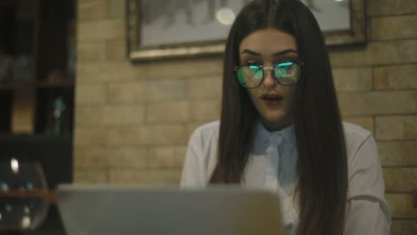 戴眼镜的年轻女商人看着笔记本电脑屏幕与快乐的惊讶表情 — 图库视频影像