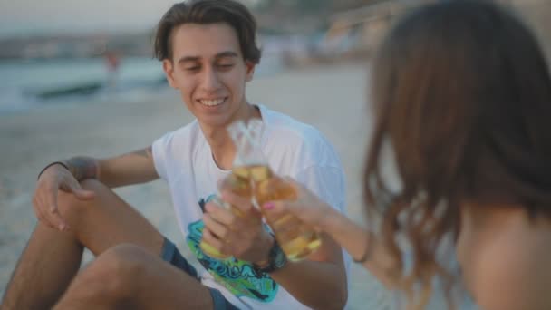 慢动作特写镜头年轻的微笑的男子在白色 T恤紧扣瓶饮料 并看着女人的眼睛在沙滩上 — 图库视频影像