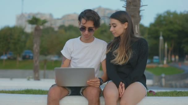 年轻的浪漫夫妇看着笔记本电脑 感觉很开心 举起手来户外 — 图库视频影像