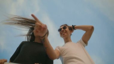 genç kadın bulutlu gökyüzü altında gülümseyen adam için gösterir