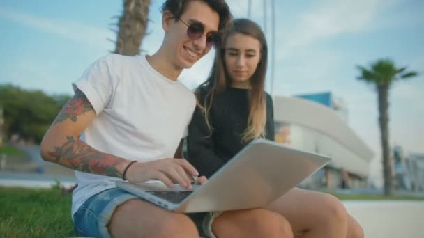 微笑的纹身家伙打开笔记本电脑和笑显示图像的女朋友 — 图库视频影像