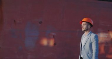 ' çerçeve günbatımı ışığı kahverengi bulanık duvara karşı adam gri iş takım elbise ve turuncu kask içinde görüntülenen