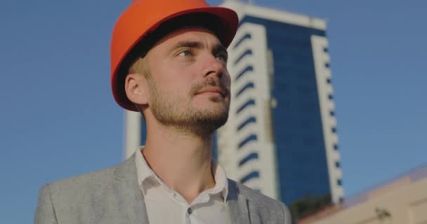 Sluiten Ingenieur Met Designer Stoppels Oranje Helm Kijkt Naar Afstand — Stockvideo
