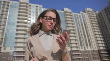 Gözlük kadın modern konut bina karşı Smartphone bakıyor yürüyor 