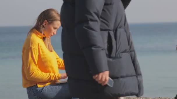 海による障壁の上に座ってラップトップ上魅力的な金髪女性のテキスト は歩く前景 — ストック動画