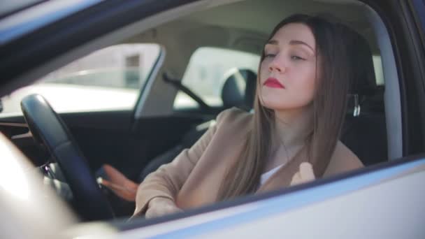 赤い口紅ブラシを持つエキサイティングな女性は 白い車のサイドミラーに見て長い緩い茶色の髪 — ストック動画