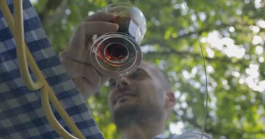 Genç adam soğuk kahve içiyor. Summerpark Kafe manzaralı. Cam masa manzaralı.