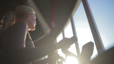 At kuyruklu güzel bir kız modern spor salonundaki geniş pencereli Velosimulator 'da kardiyo yapıyor.