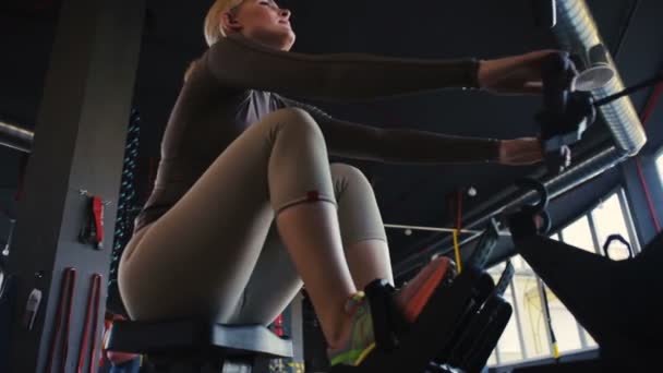 Professionele Blonde Sportvrouw Beige Sportpak Oefeningen Moderne Roeimachine Lege Fitnessruimte — Stockvideo