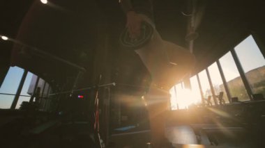 Güzel bayan silueti, pencerenin dışında küçük diskleri tutan desteğe basıyor. Düşük açılı çekim yavaş çekim.