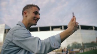 Kısa saçlı mutlu adam modern telefon ve dalgaları elinde tutuyor.