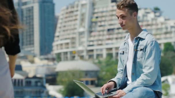 Man zit op parapet met notebook en ontmoet donkerharige dame — Stockvideo