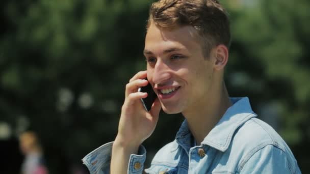 Homem com corte de cabelo curto e dentes perfeitos fala por telefone — Vídeo de Stock