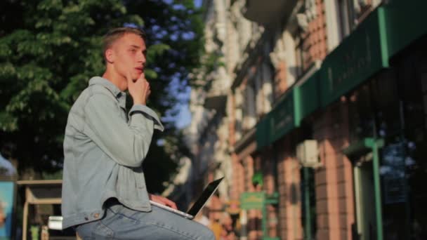 Junger Mann hält Hand in Kinn und beginnt zu tippen — Stockvideo