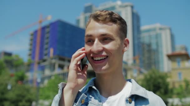 Mladý muž v džínové bundě vezme telefon a začne mluvit — Stock video