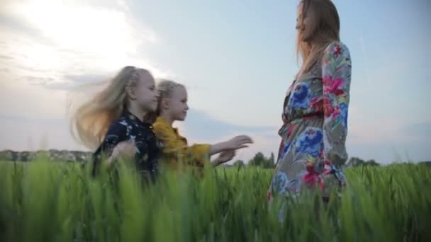 Girls with fair hair in pretty dresses hug young mother — Stock Video