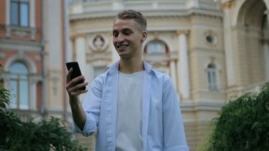 Tişörtlü gülümseyen adam şehir binasına karşı çağrıya cevap verdi