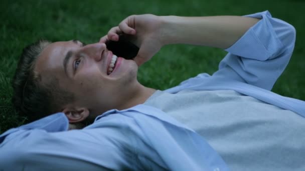 Usmívající se chlap v modré košili mluví o moderní smartphone detailní up — Stock video