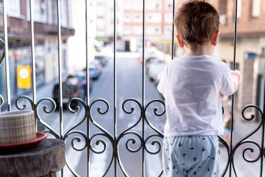 Çocuk karantinada balkondan dışarı bakıyor. İyi günler..