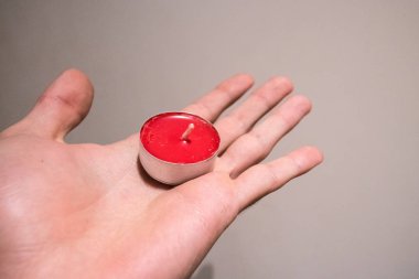 Kırmızı çay tutun düz arka plan üzerinde elinde olmak mum