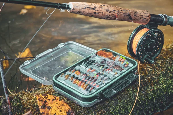 Fly rod and fly box on the bank of the stream.