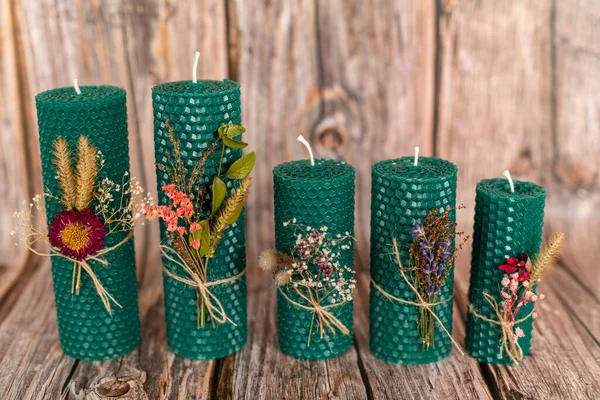 Green honey candles handmade from natural wax on a background of wooden boards. Elements from natural materials. Christmas or New Years composition. Photo for postcards.