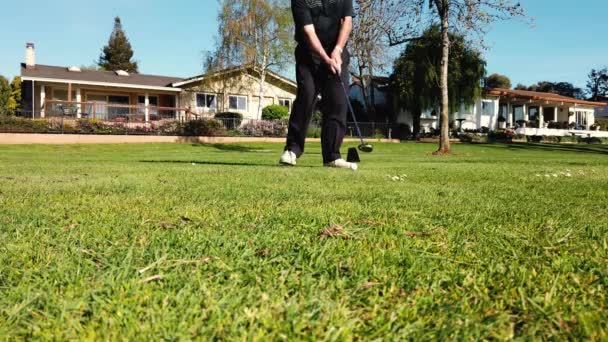Golfer dává golfový míč do díry na zeleném golfovém hřišti na kopcích v otevřené soutěži turnaje. Hráč, který drží golfový klub a chodí hrát na zelenou na letních prázdninách — Stock video