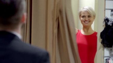 Kadın giyim mağazasında kırmızı elbise üzerinde çalışırken seksi sarışın ve onun nişanlısı gösterir. Adam elbise sevmiyorum
