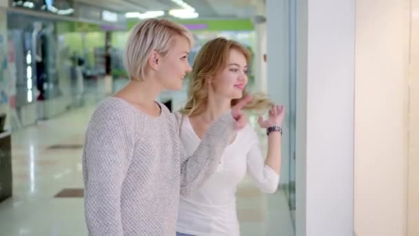 Verkauf, Konsum und Menschenkonzept - glückliche junge Frauen zeigen mit dem Finger auf Schaufenster in der Stadt — Stockvideo