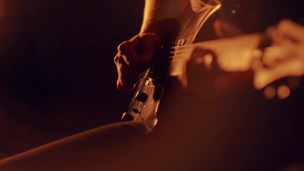 Mãos humanas a tocar guitarra eléctrica. Close up de músico de rock tocando guitarra no palco com iluminação cênica. Baixista tocando guitarra baixo elétrico. Dedos nas cordas da guitarra — Vídeo de Stock