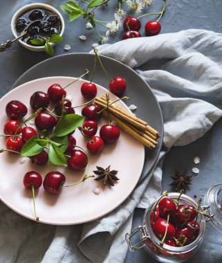 ahşap masa üzerinde çiçekler ile pembe ve gri plaka üzerinde kiraz berry