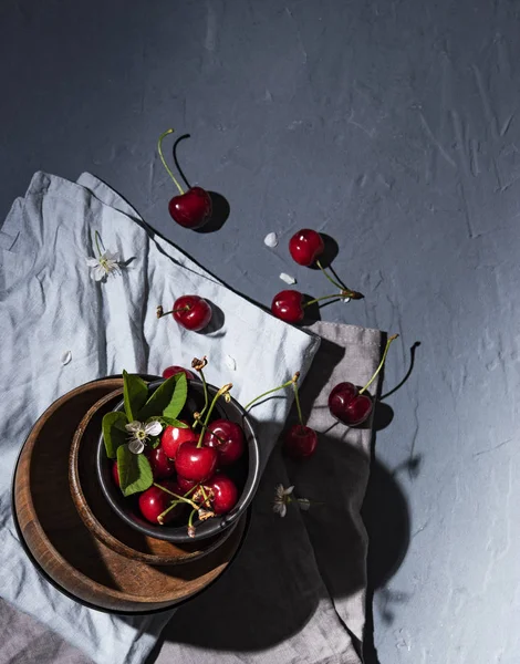 Jagoda Wiśniowa na drewnianym miskę z kwiatami na szarym stole i serwetce — Zdjęcie stockowe