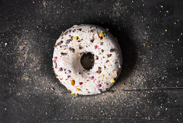 Solo delicioso donut sobre fondo oscuro con colorido espolvorear — Foto de Stock