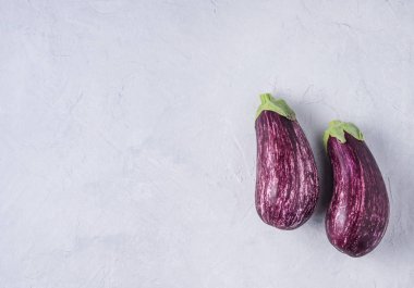 İki sulu patlıcan grafitisi gri beton masa üzerinde duruyor.