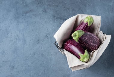 Üç sulu patlıcan grafitisi sepette gri peçeteyle duruyor. 