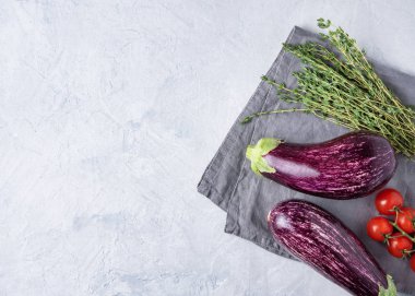 Kiraz domatesli ve kekikli iki sulu patlıcan gri bir peçetenin üzerinde yatıyor.