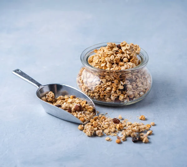 Zelfgemaakte granola met noten in een glazen pot op blauwe achtergrond. — Stockfoto