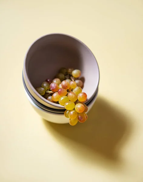 黄色の背景の灰色のボウルにジューシーな緑のピンクのブドウの塊 トップ表示とコピースペース — ストック写真