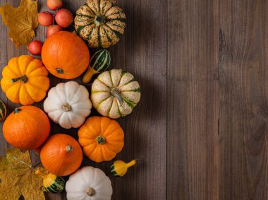 Biraz dekoratif renkli balkabağı ve ahşap kahverengi arka planda yaprak. Üst görünüm ve kopyalama alanı