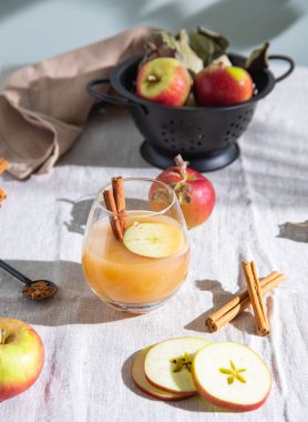 Bir bardak taze elma suyu elma dilimleri ve keten masa örtüsü üzerine tarçın. Makro görünüm ve kapatma
