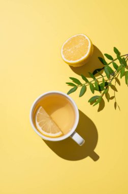 Sarı arka planda beyaz bardakta limonlu bitki çayı. Dokunulmazlık için detoks içeceği konsepti. Üst görünüm ve kopyalama alanı.