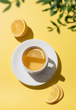 Beyaz bardakta limonlu bitki çayı turunçgil ve dilimli sarı arka planda. Dokunulmazlık için detoks içeceği konsepti. Üst görünüm ve kopyalama alanı.
