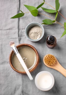 Mavi kil, fırça, mum ve keten arka planda dalla organik kozmetik yatıyordu. Ev yapımı cilt bakım ürünleri hazırlama konsepti. Üst görünüm.