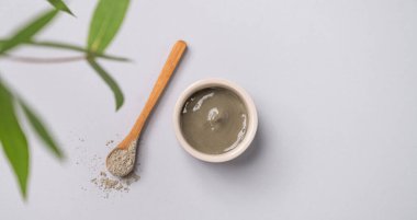 Kasede mavi kil ve arka planda yapraklı kaşık. Ev yapımı cilt bakımı organik kozmetik ürünleri ve spa tedavisi için konsept. Üst görünüm ve kopyalama alanı.