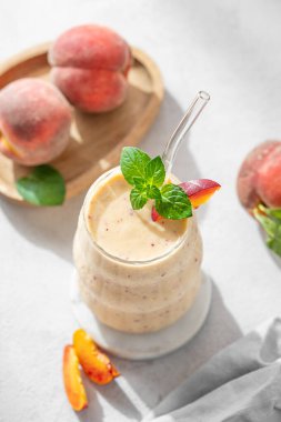 Şeftalili ve muzlu meyve püresi mermer tezgahın üzerinde tropikal meyveler ve güneş ışığıyla aydınlık bir zeminde. Reklam menüsü ya da afiş kafe için sağlıklı beslenme ve detoks diyeti kavramı. Üst görünüm, alanı kopyala.