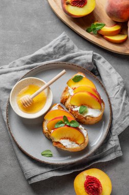 Şeftali, nektarin, krem peynir ya da ricotta ve ballı tost bruschetta taze meyve ve peçeteyle kaplanmış koyu bir tabakta. Sağlıklı yaz atıştırmalığı konsepti. Üst görünüm, alanı kopyala.