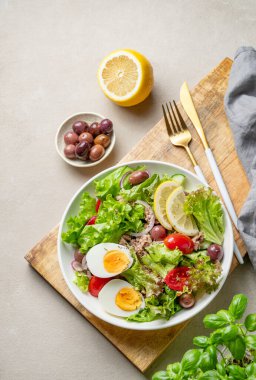 Zeytinli, marullu, domatesli, yumurtalı ve limonlu ton balığı salatası. Tahta bir tabakta, hafif bir arka planda, bitki ve çatal bıçaklı. Sağlıklı beslenme ve Akdeniz diyeti kavramı. Üst görünüm, alanı kopyala.